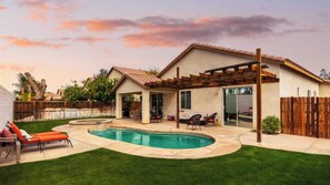 Un jardin avec une piscine, un patio couvert et une zone délimitée par une clôture.