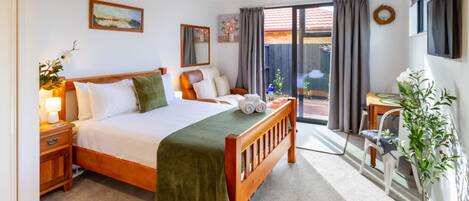 Hotelkamer met een bed, bureau, stoel, een kamerplant en uitzicht.