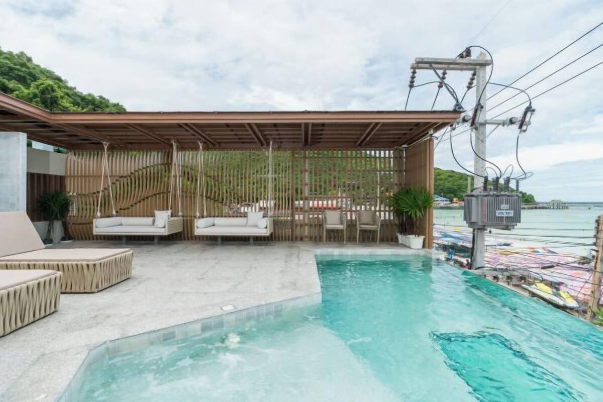 A pool area with lounge seating and a view of the sea.