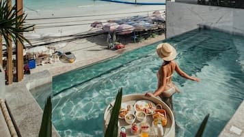 A poolside view with a dining setup and a beach in the background.