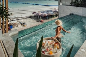 A poolside view with a dining setup and a beach in the background. - Mila Kohlarn (Koh Larn)