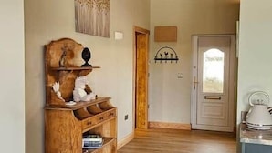 Un pasillo con piso de madera, un armario de madera, una puerta y una pequeña mesa redonda con un libro.