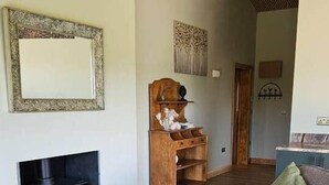 Una sala de estar acogedora con chimenea, un mueble de entretenimiento de madera, un sofá y una mesa de centro con bebidas y aperitivos.