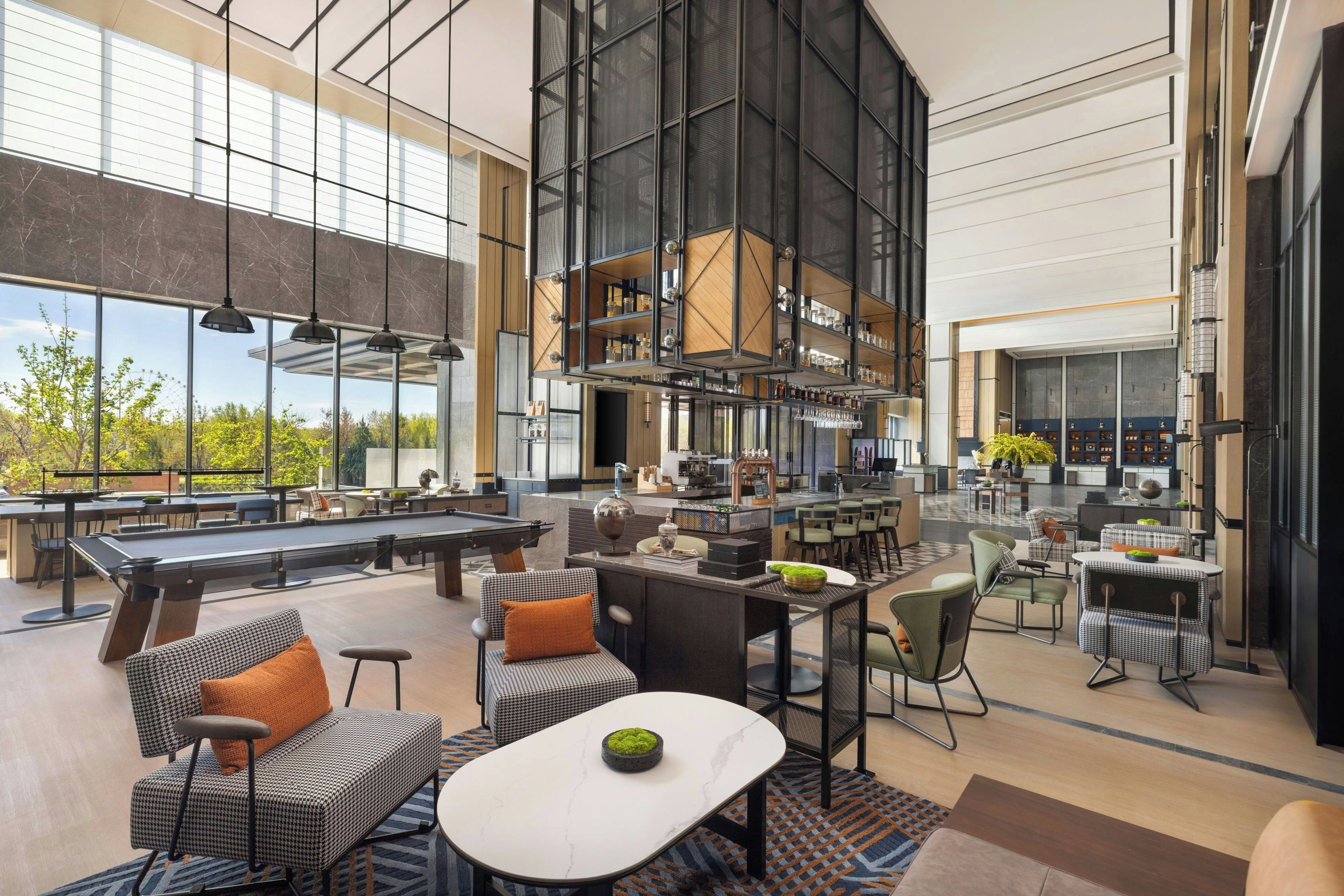 A spacious indoor area with a pool table, seating arrangements, and a bar area with shelves.