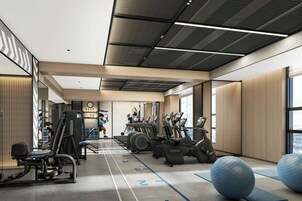 Une salle de sport moderne équipée de matériel d’exercice, dotée d’une piste d’athlétisme et de grandes fenêtres.