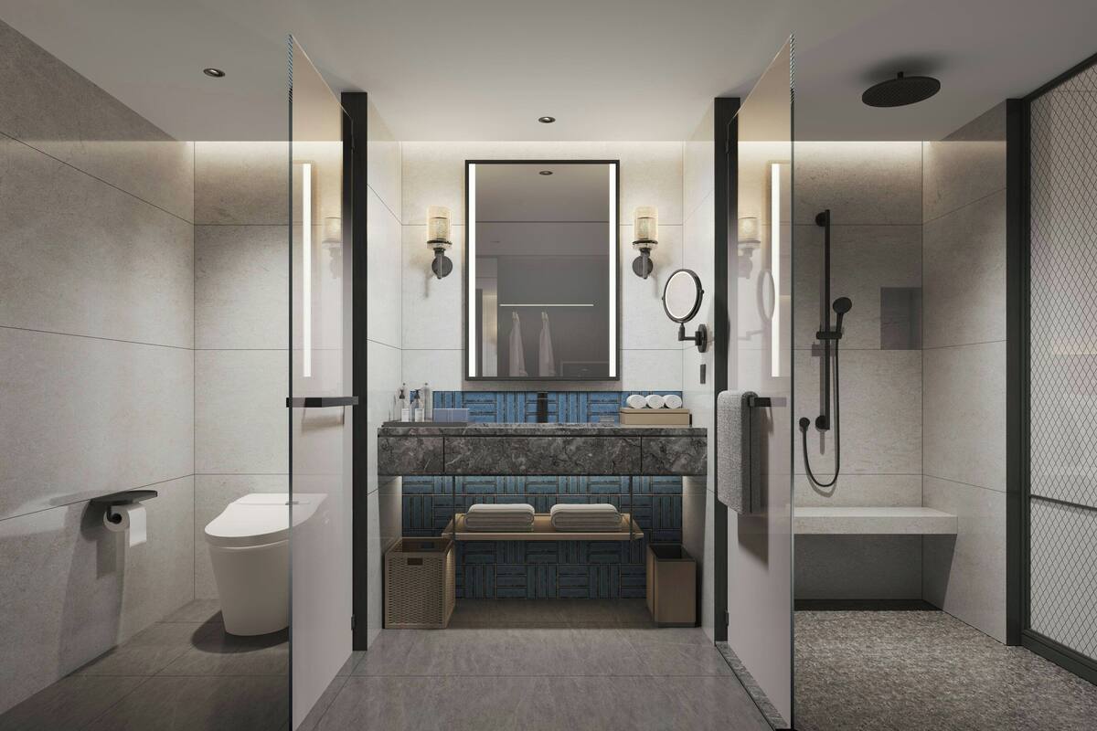 A modern bathroom with a glass partition, a toilet, a sink with a mirror, and a shower area.