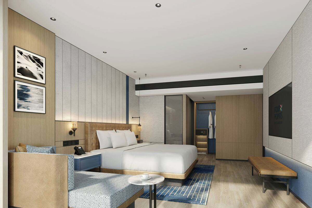 A modern hotel room with a large bed, a seating area, and a TV.
