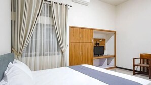 A hotel room with a bed, a wardrobe, a desk with a computer, and a chair. - RedDoorz @ RRR Guesthouse Mataram (Selaparang)