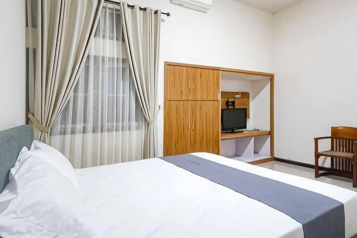 Ein Hotelzimmer mit Bett, Kleiderschrank, Schreibtisch mit Computer und Stuhl.