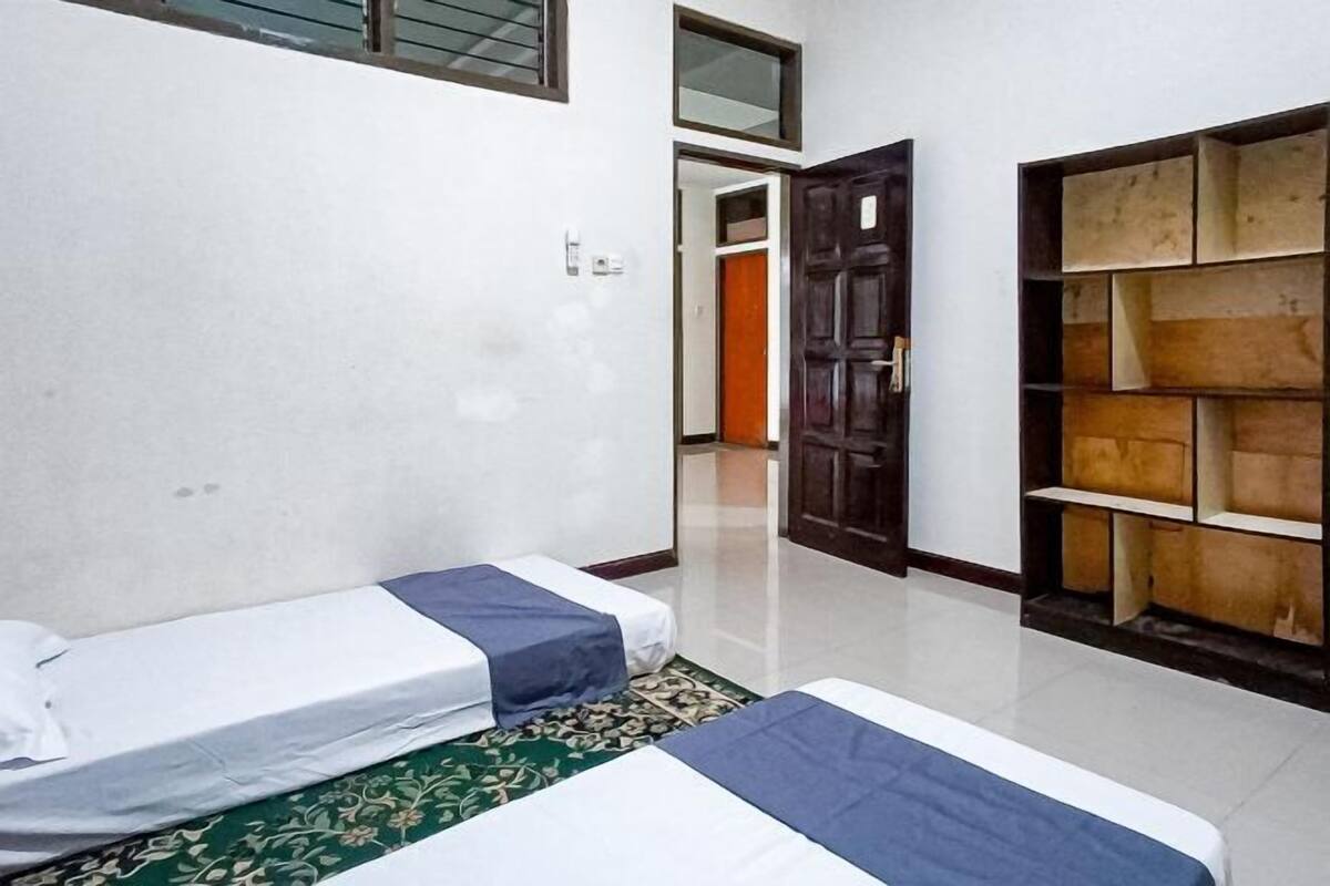 Ein Zimmer mit zwei Betten, einem Holzschrank und einer Tür zu einem weiteren Raum.