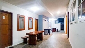 A hallway with patterned flooring, wooden benches, and doors with windows. - RedDoorz @ RRR Guesthouse Mataram (Selaparang)