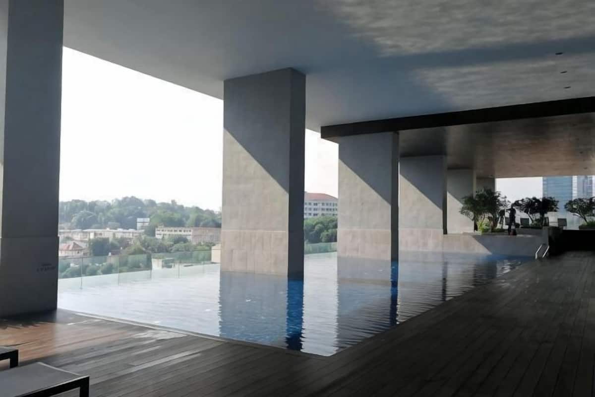 Una amplia piscina interior con techos altos y grandes pilares de concreto, con vistas a la ciudad.