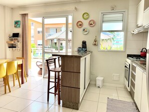 A kitchen with a dining area, a small island, and a view of the outside. - Soothing apartment  near the beach in Ingleses with pool views (Florianópolis)