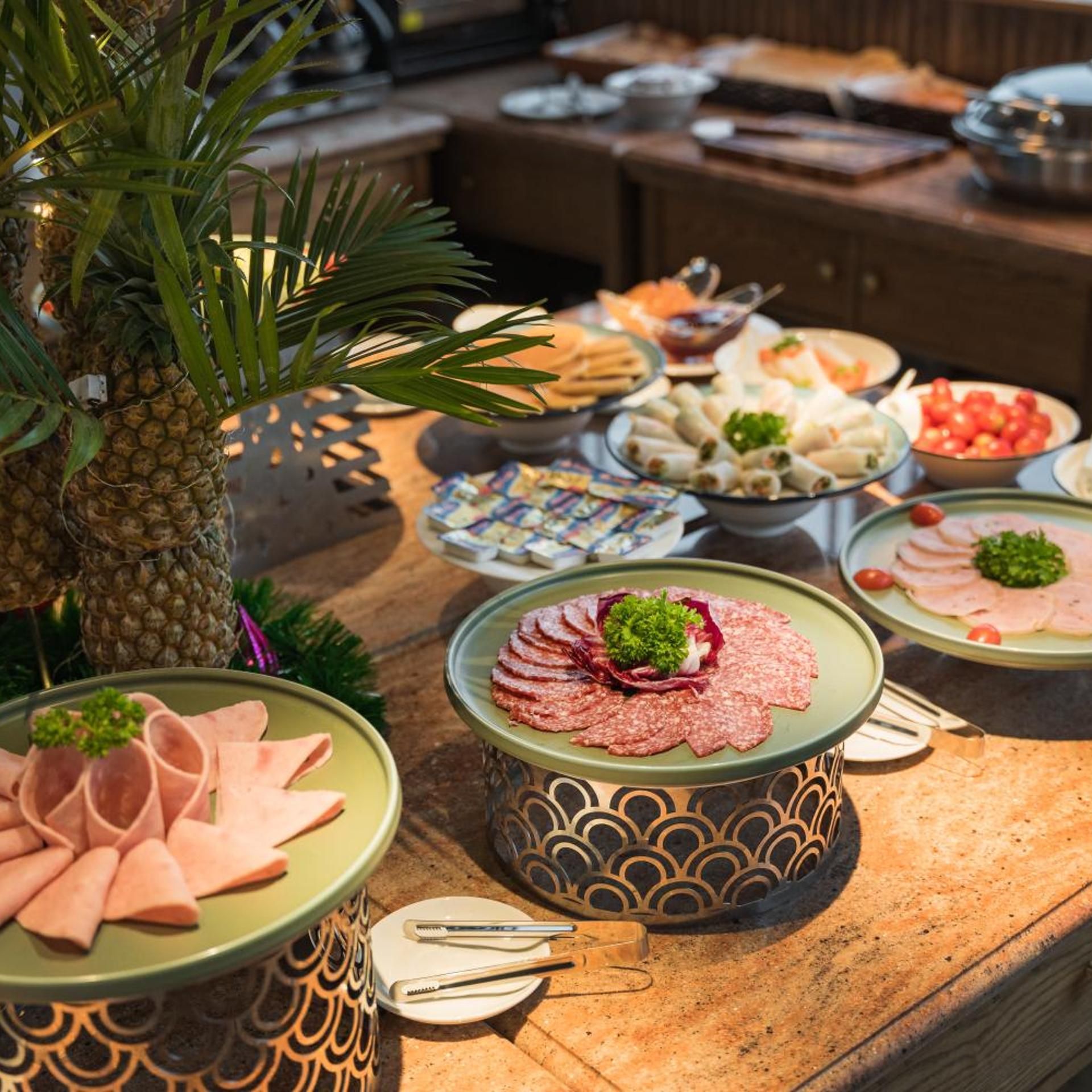 Ein Buffet mit verschiedenen Speisen, darunter Aufschnitt und Gemüse.