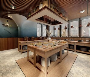 A restaurant with a high ceiling, wooden beams, and a central serving table with food and drinks. - La Passion Hanoi Hotel & Spa (Hanoi)