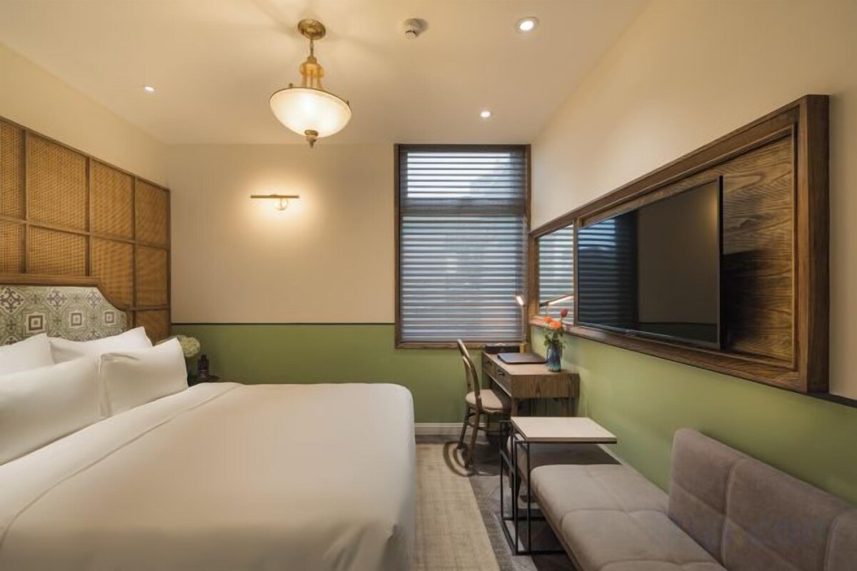 A hotel room with a bed, a desk, a chair, and a sofa.