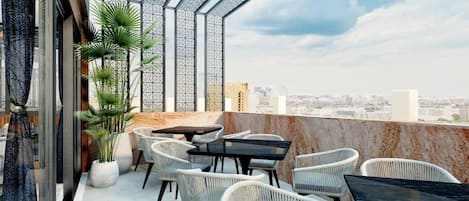 Een terras op het dak met buitenmeubilair, uitzicht over de stad en een decoratief metalen dak.