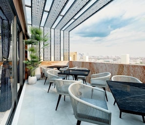 A rooftop terrace with outdoor seating, a city view, and a decorative metal ceiling.