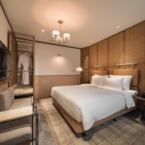 A hotel room with a bed, a seating area, a wardrobe, and a wall-mounted light fixture. - La Passion Hanoi Hotel & Spa (Hanoi)