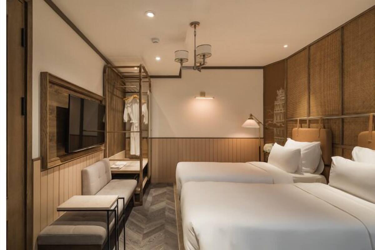 Ein Hotelzimmer mit Bett, Schreibtisch, Sessel, Fernseher und Kleiderschrank.