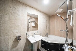 Un baño con lavamanos, bañera y ducha.