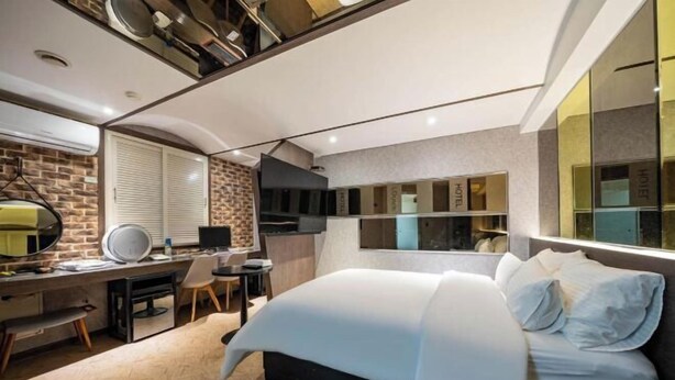 Une chambre moderne avec un lit, un bureau et un coin salon.