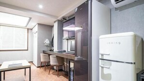 Une cuisine compacte comprenant un réfrigérateur, une table à manger, des chaises et une fenêtre.