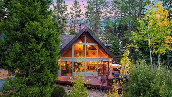 A cabin with a large glass front, wooden deck, and surrounded by trees. - Classic A-frame Cabin w/ Hot Tub + Deck & Easy Access Near Ski + Lake Summit Haven by Avantstay (Tahoe City)
