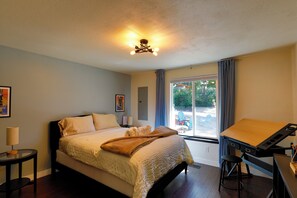 A bedroom with a bed, a desk, and a window with curtains.