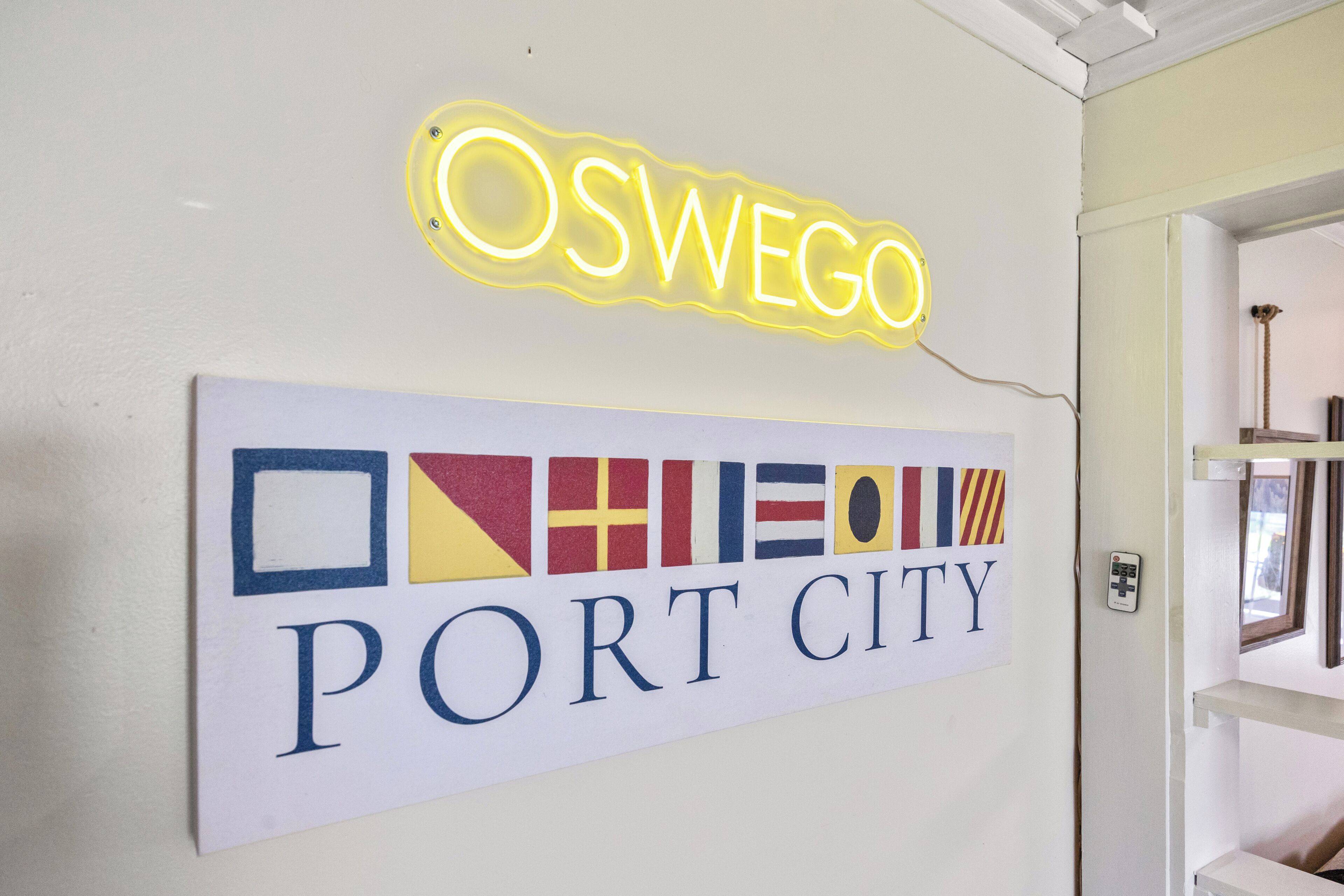 Een neonbord waarop 'OSWEGO' staat, en een bord met vlaggen en de tekst 'PORT CITY'.