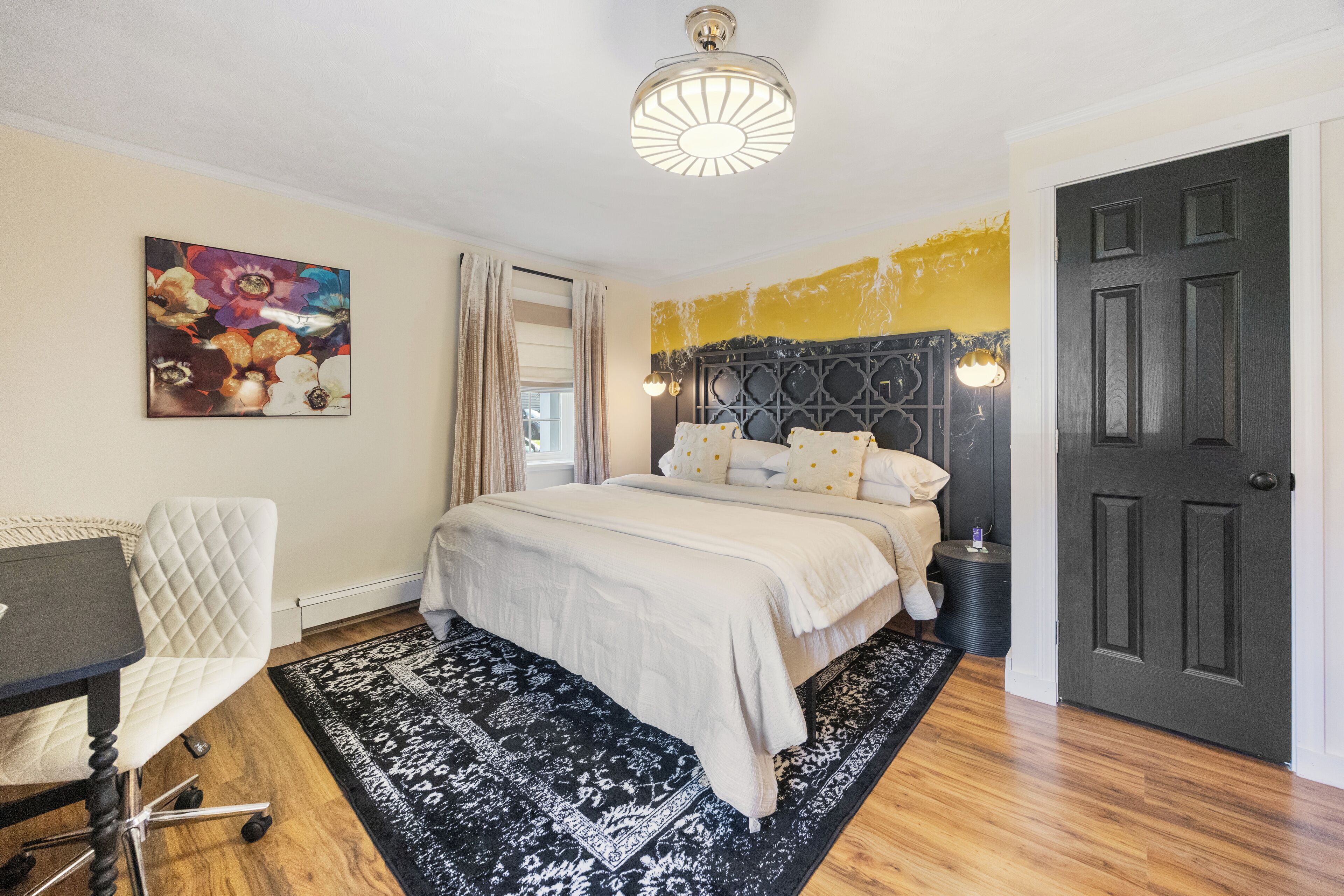 Une chambre à coucher avec un lit, un bureau, une chaise, un tapis et un tableau accroché au mur.