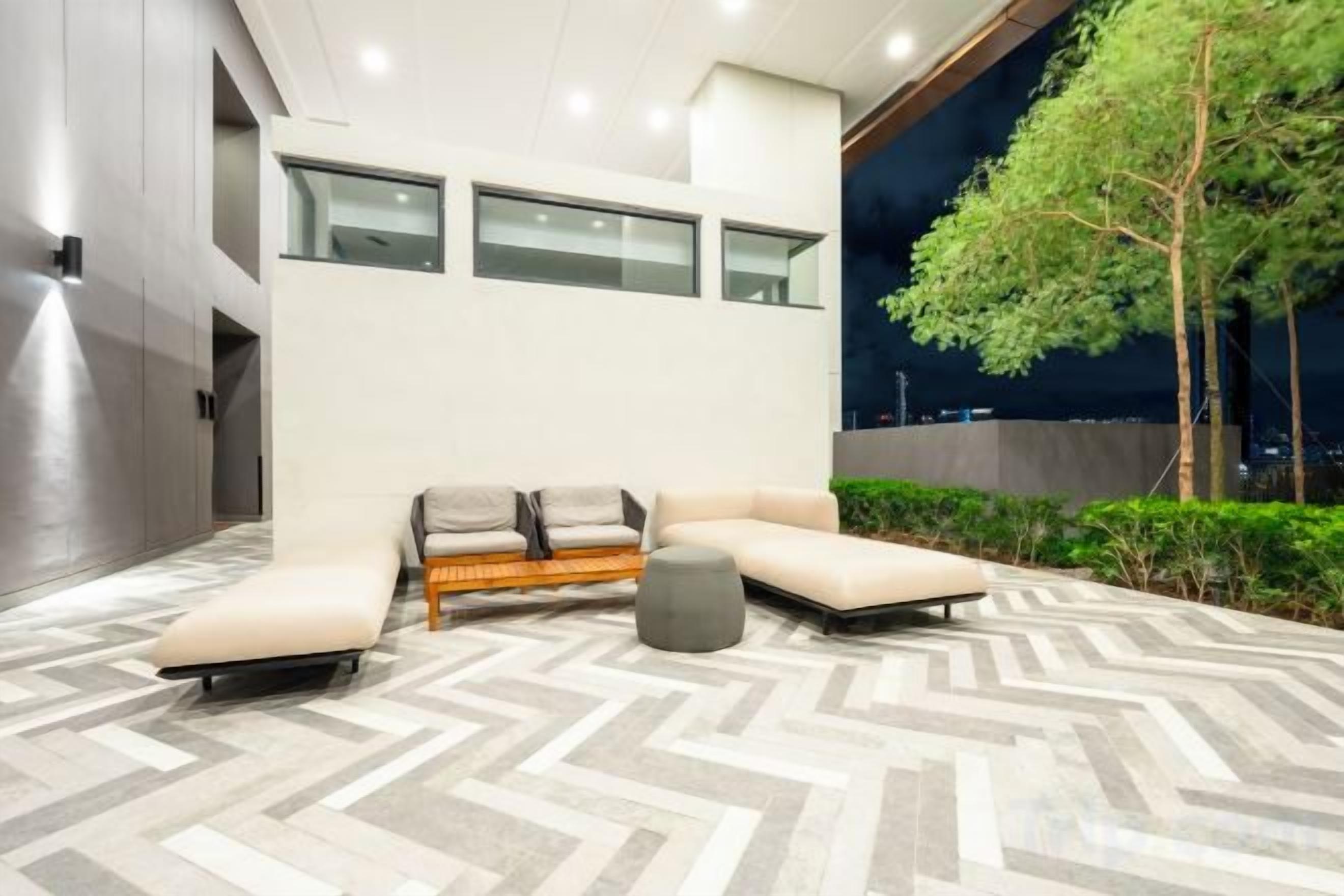 A modern outdoor lounge area with a herringbone-patterned floor, a sofa set, and a tree.