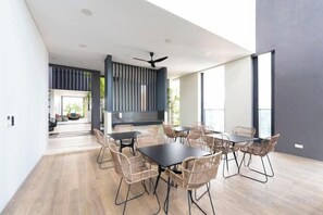 A modern dining area with a black table and wicker chairs, a ceiling fan, and large windows. - Harmony Luxury Suites At Lucentia Bukit Bintang City Center (Kuala Lumpur)