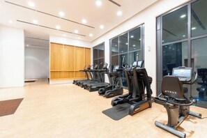 A gym with treadmills lined up against a wall with large windows. - Harmony Luxury Suites At Lucentia Bukit Bintang City Center (Kuala Lumpur)