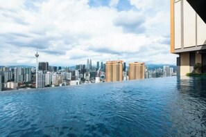 A rooftop infinity pool with a city skyline view. - Harmony Luxury Suites At Lucentia Bukit Bintang City Center (Kuala Lumpur)