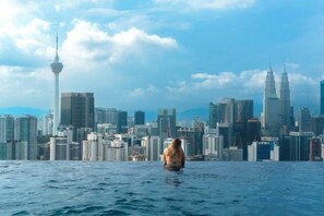 A person sitting on a water body with a cityscape in the background. - Harmony Luxury Suites At Lucentia Bukit Bintang City Center (Kuala Lumpur)