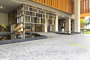 A modern building with a glass facade, a central water feature, and a paved courtyard. - Harmony Luxury Suites At Lucentia Bukit Bintang City Center (Kuala Lumpur)