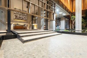 A spacious lobby with a reception desk, a staircase, and a large window. - Harmony Luxury Suites At Lucentia Bukit Bintang City Center (Kuala Lumpur)