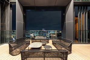 A rooftop terrace with wicker furniture and a city view at night. - Harmony Luxury Suites At Lucentia Bukit Bintang City Center (Kuala Lumpur)