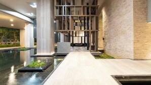 A modern indoor pool area with a central walkway, surrounded by stone walls and minimalist wooden structures. - Harmony Luxury Suites At Lucentia Bukit Bintang City Center (Kuala Lumpur)