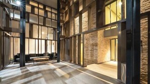 A spacious lobby with a high ceiling, wooden flooring, and a seating area with a sofa and chairs. - Harmony Luxury Suites At Lucentia Bukit Bintang City Center (Kuala Lumpur)