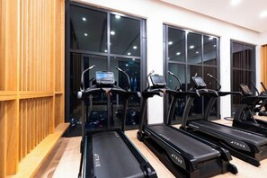 A gym with treadmills and exercise equipment, large windows, and a wooden wall. - Harmony Luxury Suites At Lucentia Bukit Bintang City Center (Kuala Lumpur)