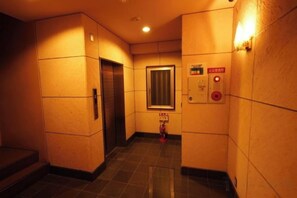 A hallway with a door, a fire alarm, and a light switch. - AIROSE Yodoyabashi (Osaka)