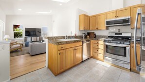 A modern kitchen with wooden cabinets, stainless steel appliances, and a granite countertop. - Sleeps 8 in the Jewell Box close to Privates and Pleasure Point (Santa Cruz)