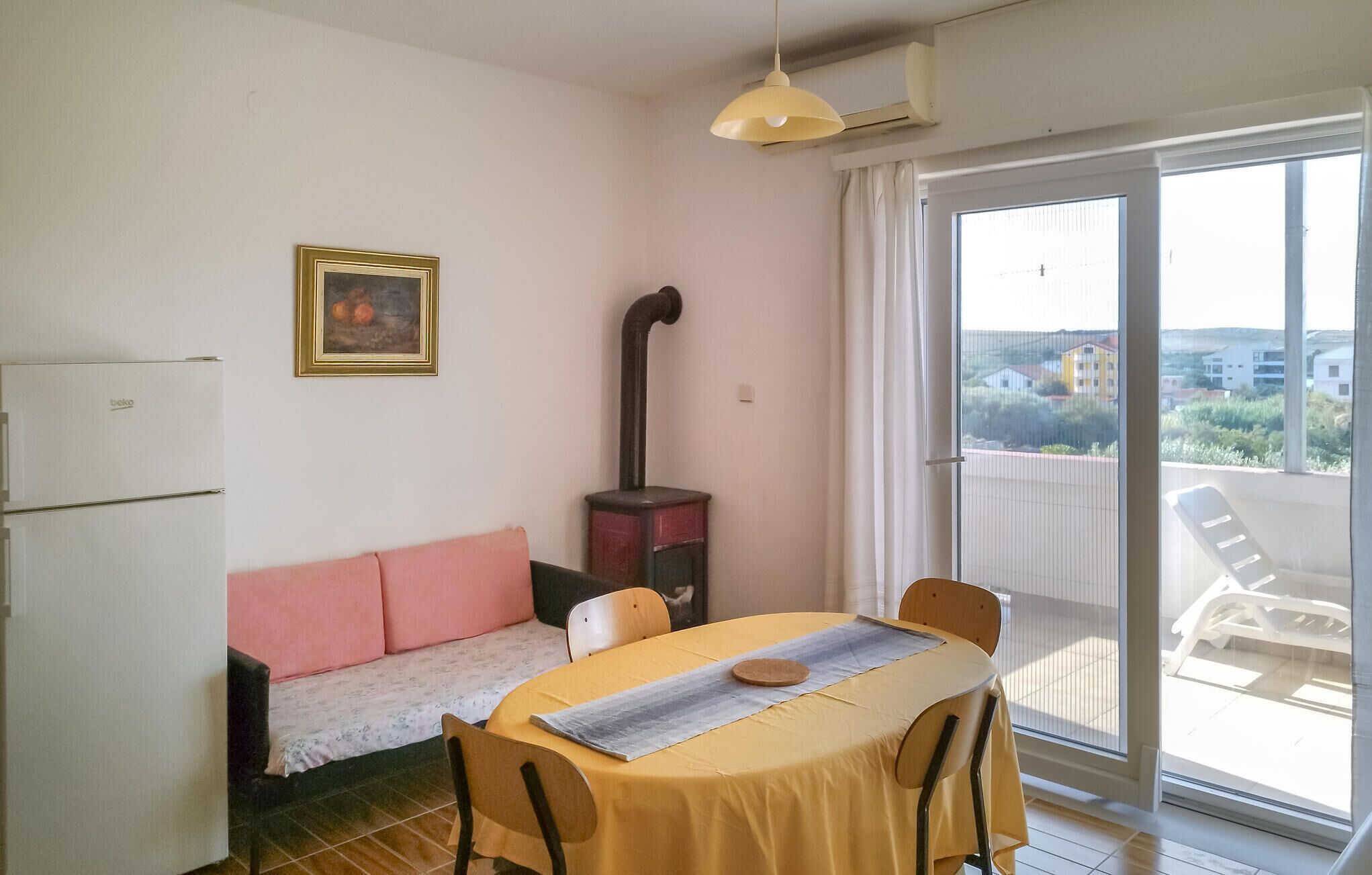 Un ambiente compatto con tavolo da pranzo, divano, angolo cottura e vista tramite una porta scorrevole in vetro.