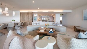 A modern living room with a large L-shaped sofa, multiple seating options, and a central coffee table. - Condo Surf Sea Streich (Punta Mita)