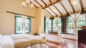 Un dormitorio con una cama grande, un banco de madera y un escritorio con sillas.