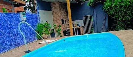 A rectangular swimming pool with a tiled deck surrounding it.