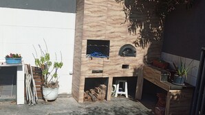 A small, enclosed outdoor area with a wooden bench, potted plants, and a small fireplace. - Townhouse with pool and air conditioning near Caraguatatuba shopping mall (Caraguatatuba)