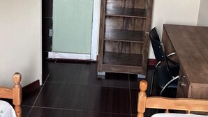Une pièce comprenant un lit, une armoire en bois, un bureau et une porte donnant sur une autre pièce.